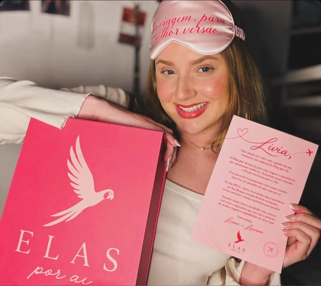 A Lívia sorrindo com o kit do Elas por Aí e a carta das fundadoras